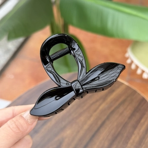 Close-up of glossy black leaf bow hair claw clip with strong metal spring detail