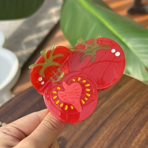 Détail macro de la pince à cheveux en acétate en forme de tomate aux couleurs vives
