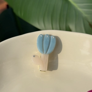 French blue tulip hair clip with rhinestones on a minimalist white ceramic bowl background