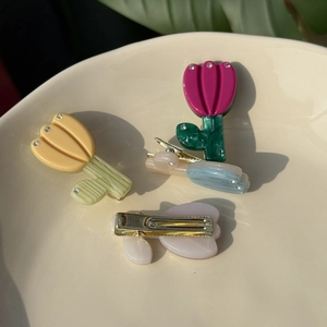 Detailed macro view of tulip acetate hair clips with crystal accents in a ceramic tray