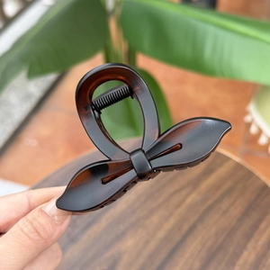 Detail view of tortoiseshell bow hair claw clip in a glossy dark brown acetate finish