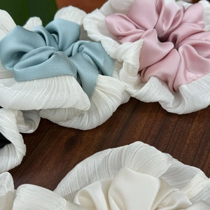 Detail of silk-like pleated chiffon scrunchies in light blue, pink and white shades