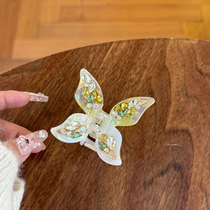 Pearlescent white butterfly hair claw clip with colorful rhinestones on wooden background
