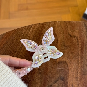 Elegant butterfly hair claw clip with colorful rhinestones on a pink resin base