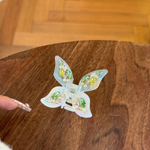 Sparkling butterfly hair claw clip with colorful rhinestones on a warm wood background