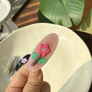 Pince à cheveux fleur en acétate rose avec strass sur un bol en céramique blanc