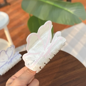 Detailed close-up of butterfly hair claw clip with floral pattern and Fancy engraving