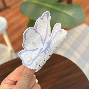 Macro view of butterfly hair claw clip featuring pearly purple acrylic texture and crystal