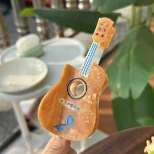 Guitar shaped amber acetate hair claw clip with colorful rhinestones and musical note detail