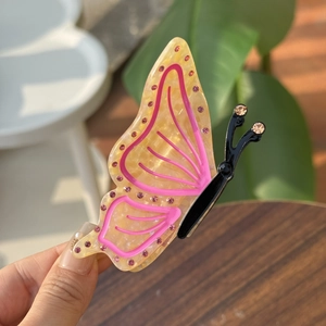 Elegante molletta a farfalla in acetato con strass rosa e finitura giallo ambra