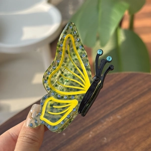 Dettaglio della molletta per capelli a farfalla verde con strass e acrilico