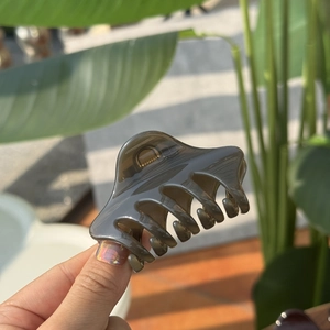 Close-up of translucent grey plastic hair claw clip showing smooth resin texture and spring