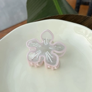 Haarklammer in Blumenform aus Acetat in Rosa mit Strass auf einem beigen Teller
