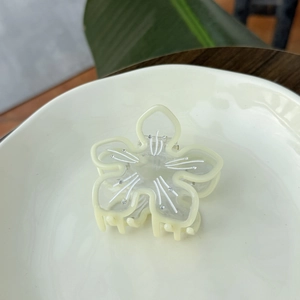 Durchscheinende cremefarbene Blumen-Haarklammer mit Strass auf weißem Keramikteller