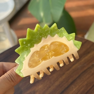 Vue macro d'une pince à cheveux en acétate en forme de durian avec coque verte texturée