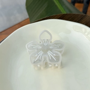 Detailansicht der lichtdurchlässigen Blumen-Haarklammer aus Acetat mit Glitzerstein-Verzierung