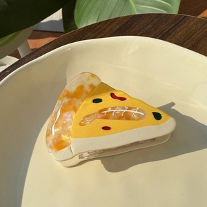 Creative pizza-shaped acetate hair claw clip presented on a white plate with leaf decor