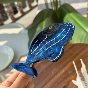 Deep blue whale-shaped acetate hair claw clip with white ocean wave patterns