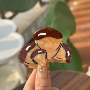 Détail d'une pince à cheveux champignon en acétate de cellulose marron à texture marbrée