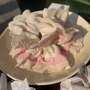 Gros plan détaillé du chouchou en satin ivoire avec une bordure en dentelle rose délicate