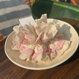 Grand chouchou élégant en dentelle beige et rose présenté sur une assiette décorative