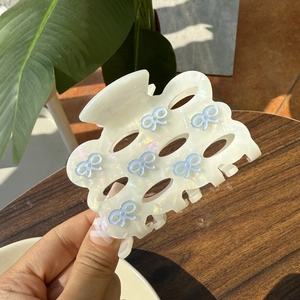 Elegante haarklem van acetaat met blauwe strikjes en marmeren textuurpatroon