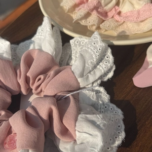 Détail d'un chouchou rose en tissu avec dentelle blanche et décoration de bouton lapin