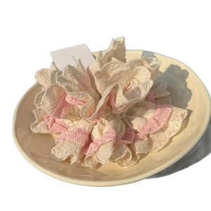 Chouchou crème avec dentelle rose dans un plat en céramique, accessoire élégant