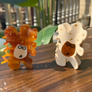 Détails des pinces à cheveux ours en acétate ambre et blanc crème sur bois poli