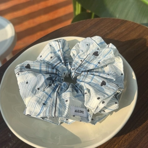 Chouchou à carreaux bleu et blanc avec motif cœur posé sur un plateau en céramique
