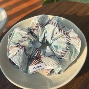 Chouchou surdimensionné à carreaux bleu et marron avec strass sur assiette blanche