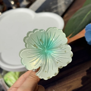Detail showing the iridescent green floral hair claw clip with a pearlescent finish