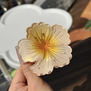 Close-up of a gradient amber floral hair claw clip with delicate pearlescent glitter finish