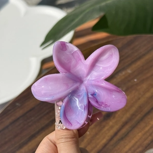 Dettaglio di un fermaglio per capelli a fiore di frangipane viola effetto marmo