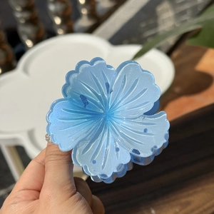 Detailed close-up of a blue resin flower hair claw clip with subtle glitter shimmer finish