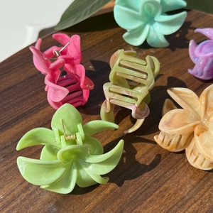 Dettaglio macro di pinze per capelli a forma di fiore con trama marmorizzata su legno