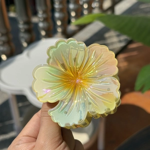 Detail showing the iridescent yellow flower hair claw clip with a pearlescent finish