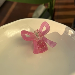 Détail d'une pince à cheveux papillon rose translucide avec une finition en résine