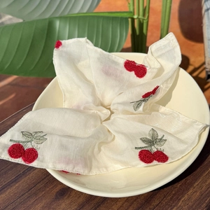 Elegant off-white lace scrunchie with cherry embroidery in a rustic ceramic bowl