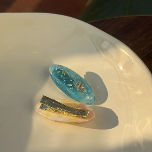 Handgefertigte Harz-Haarspangen-Set mit Muscheln und goldenen Seesternen auf Keramik