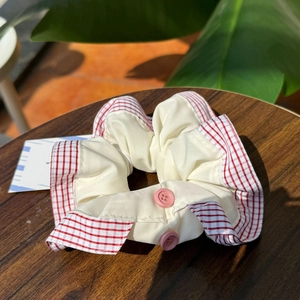 British style cream hair scrunchie with red plaid edges and pink button accents