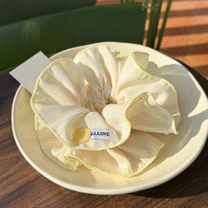 Striped yellow flower scrunchie with button detail and branding in a ceramic plate