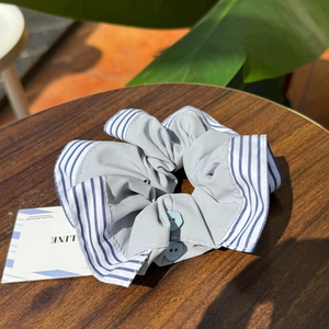 Creative plaid scrunchie with shirt cuff design and blue buttons on wooden background
