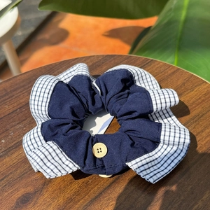 British style plaid scrunchie with a wooden button on a rustic wooden background