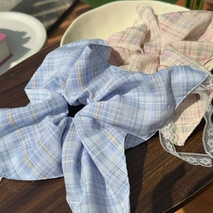 Close-up of oversized plaid scrunchies with white lace edges in light blue and pink tones