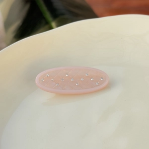 Pince à cheveux ovale rose avec motif losange sur plat en céramique crème