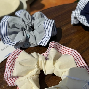 Detailed view of handmade plaid scrunchies with decorative buttons and striped fabric edges