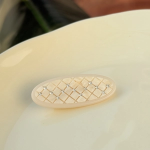 Détail d'une pince à cheveux ovale matelassée ornée de petits strass blancs