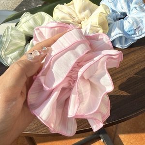 Macro shot of striped chiffon scrunchies with heart buttons and brand woven labels