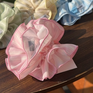 Detailed close-up of striped chiffon ruffle scrunchies in pastel colors on wood surface